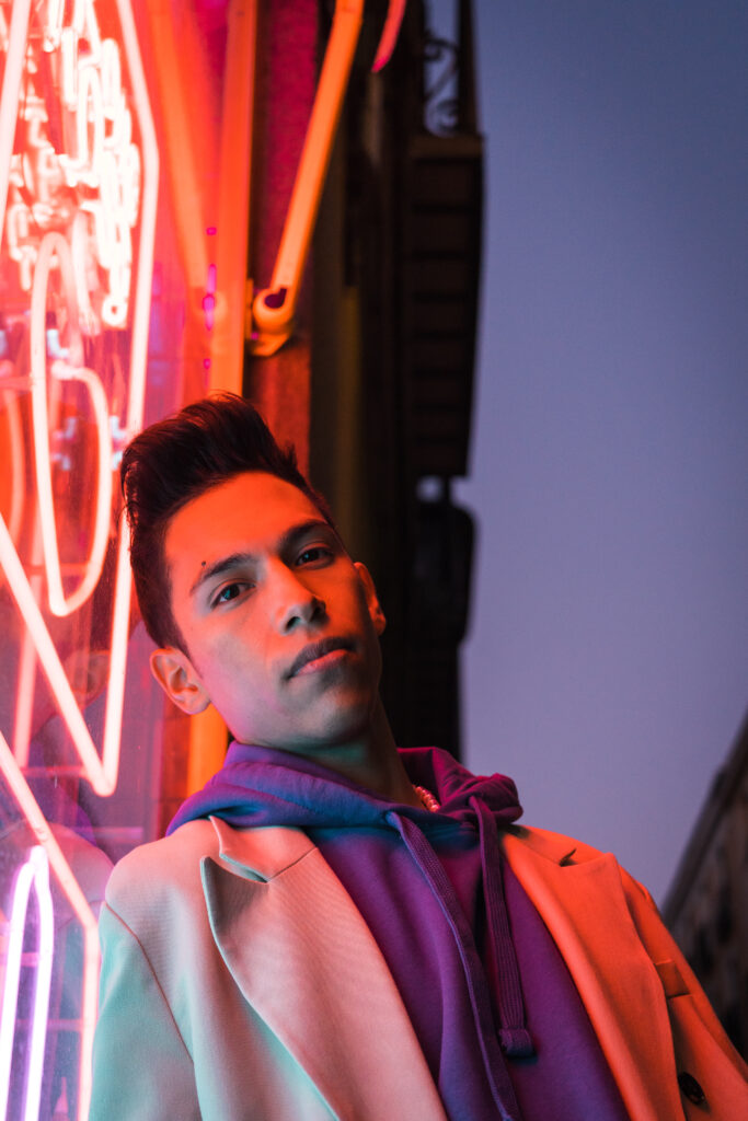 Portrait of young hispanic man with red neon light on the face